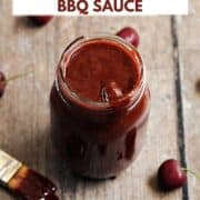 Cherry chipotle bbq sauce in a glass mason jar surrounded by fresh cherries with title graphic across the top.