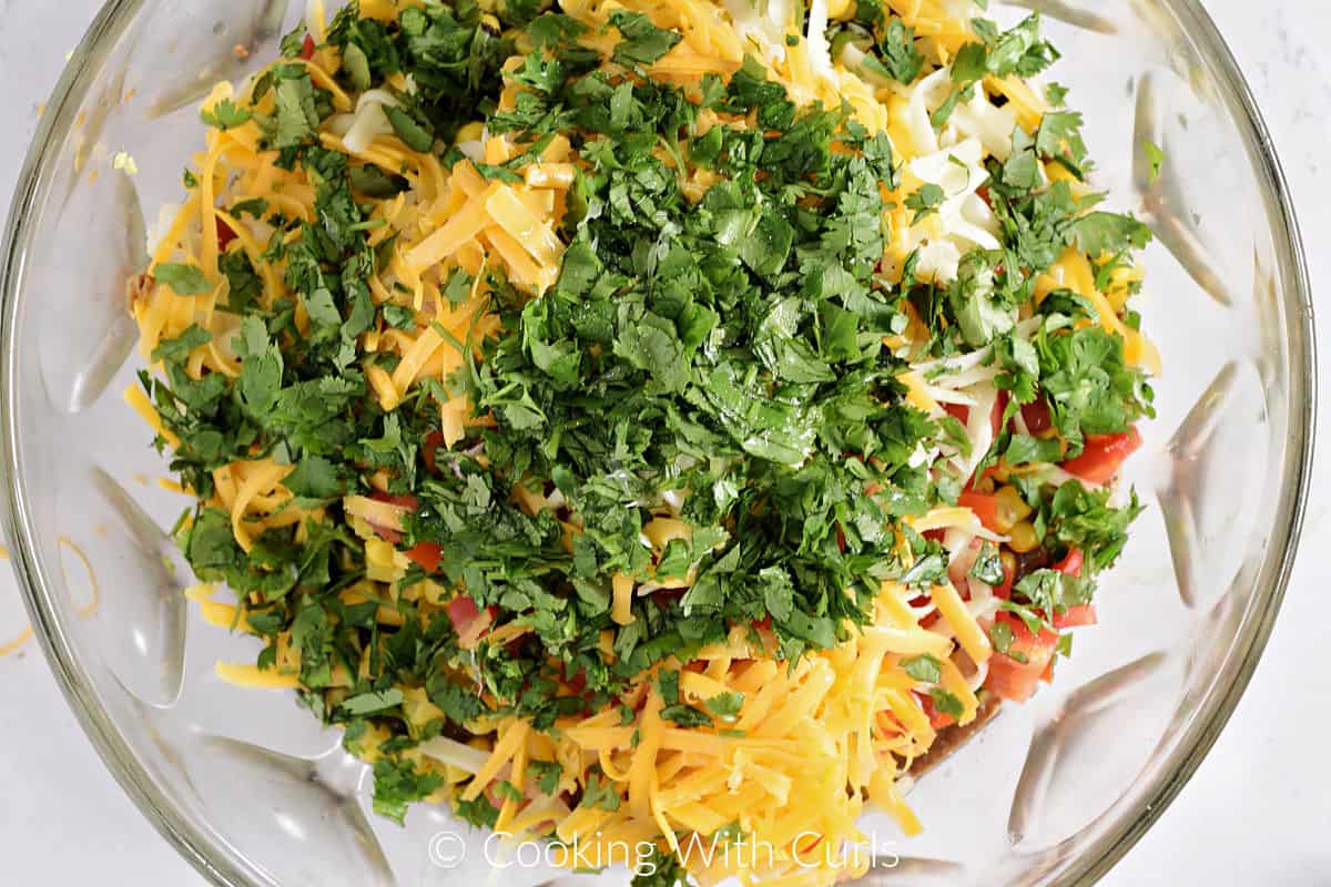 Chopped cilantro, grated cheeses, diced tomatoes, and corn in a large mixing bowl. 