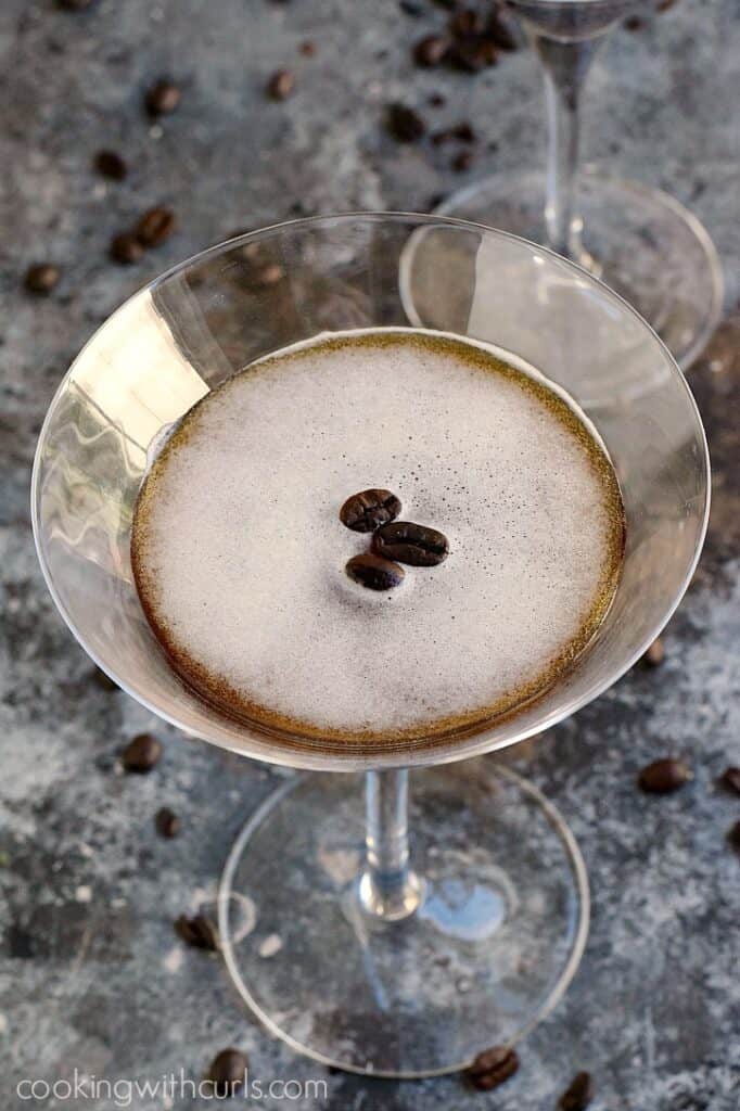 Espresso martini in a martini glass with with three coffee beans floating on top.