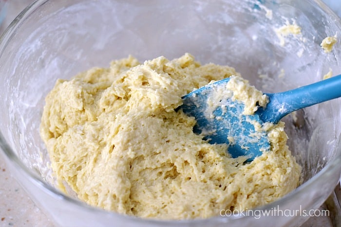 Muffin batter mixed with a rubber spatula in a large glass bowl.