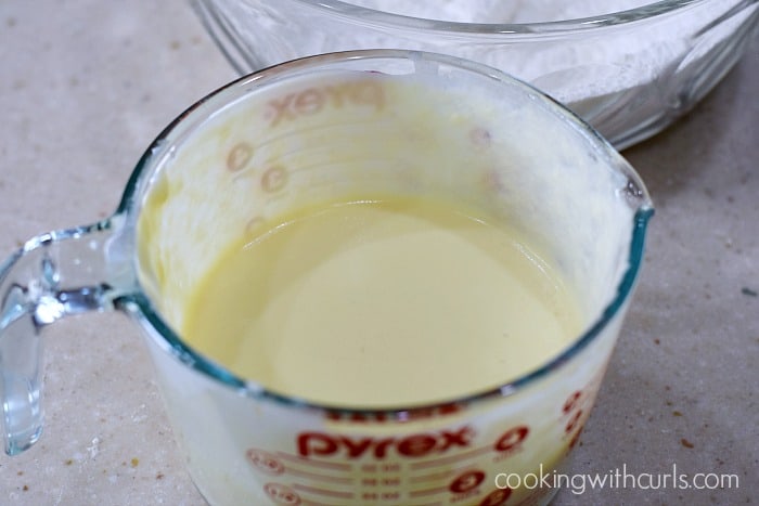 Butter, yogurt, eggs, milk, vanilla, and almond extract mixed together in a large glass measuring cup.