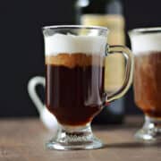 Coffee cocktail in glass mug topped with whipped cream.