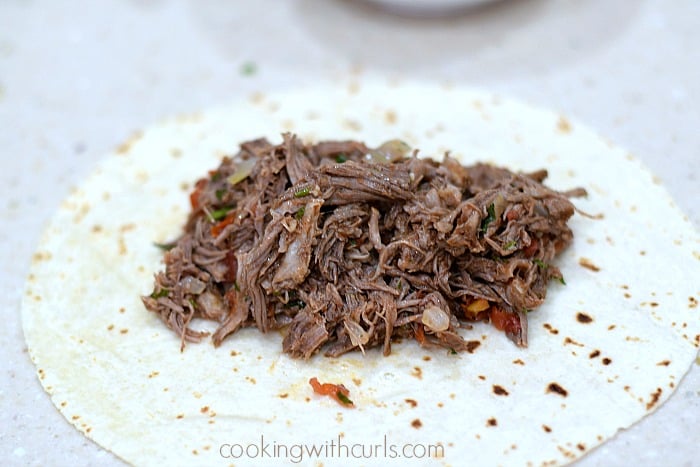 Mexican shredded beef in the center of a flour tortilla.