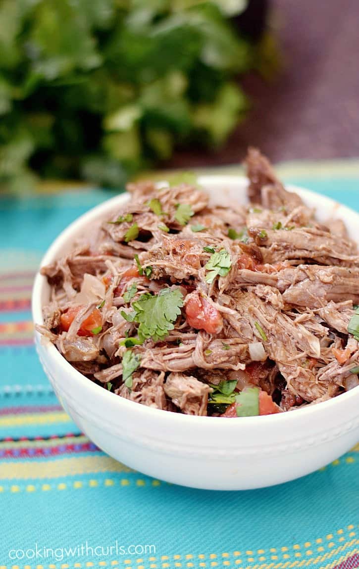 Shredded beef mixed with tomatoes, onion, and cilantro in a small bowl.