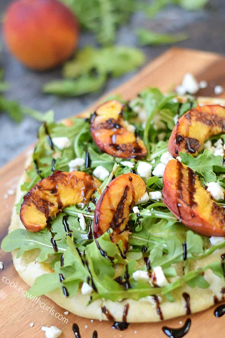 Pizza topped with grilled peaches, arugula leaves, crumbled goat cheese and balsamic drizzle.