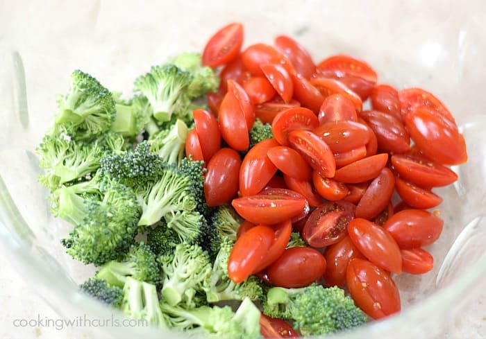 Raw broccoli florets and halved cherry tomatoes in a large mixing bowl.