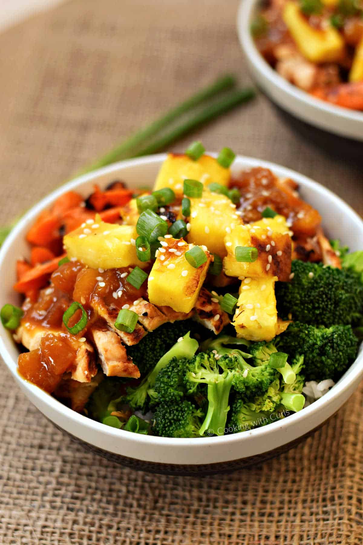 Two grilled chicken teriyaki bowls with broccoli, carrots, and pineapple chunks over rice.