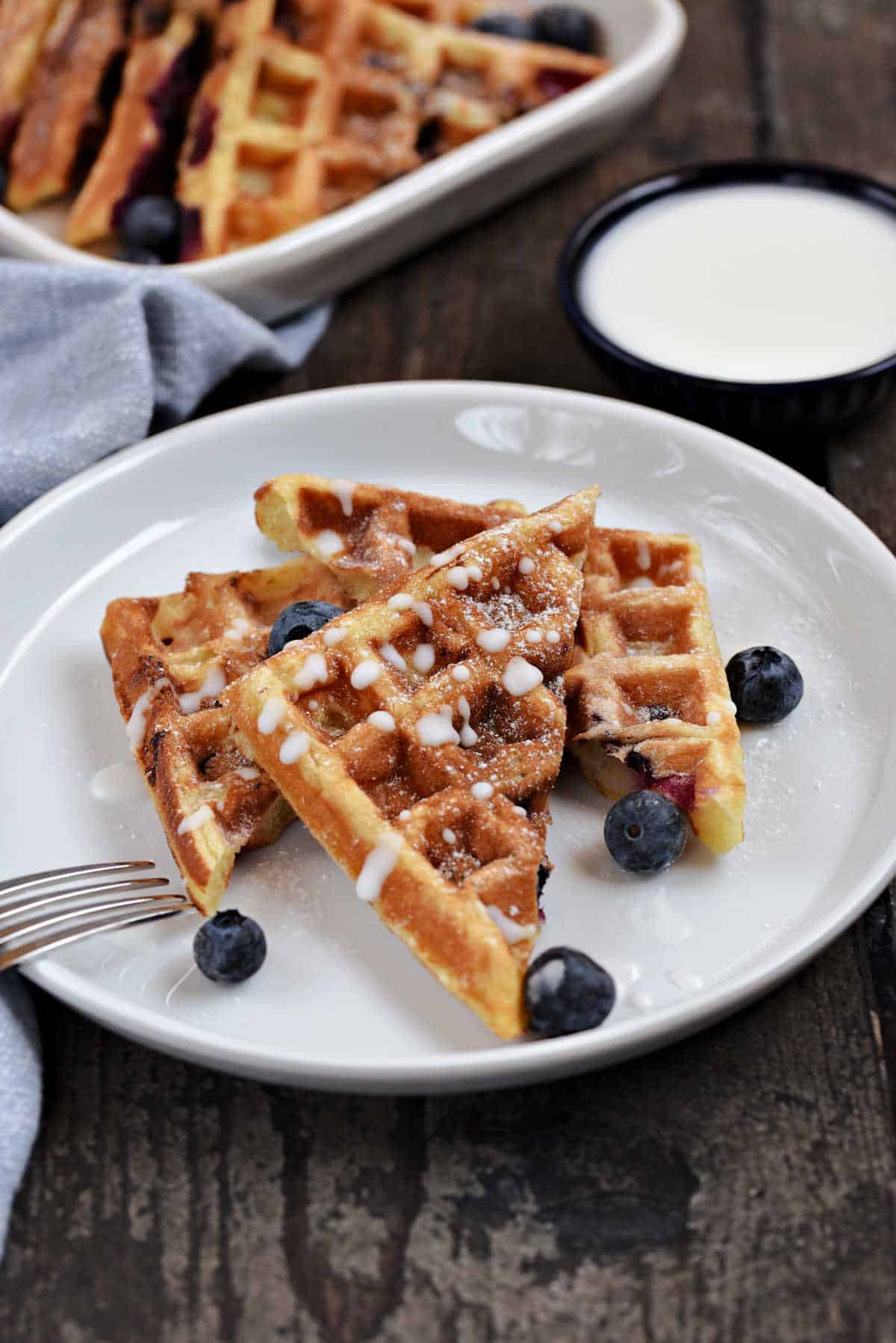 Blueberry Lemon Waffled Muffins with lemon glaze and fresh blueberries on a plate.