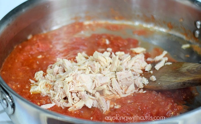 Chunked tuna added to tomato sauce in skillet.