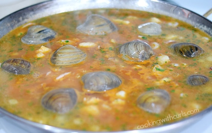 Clam shells and seafood mixture with rice in a paella pan.