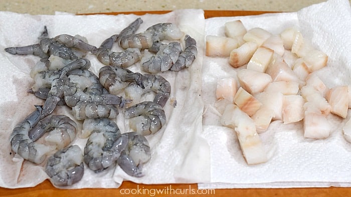 Raw shrimp and cod pieces drying on paper towels.