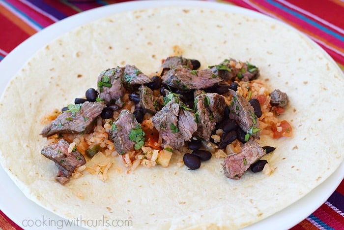 Salsa rice, grilled steak pieces and black beans on a flour tortilla.