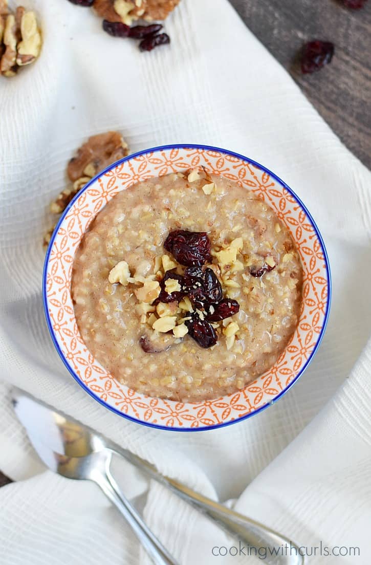 Looking down on a bowl of oatmeal topped with walnuts and cranberries.