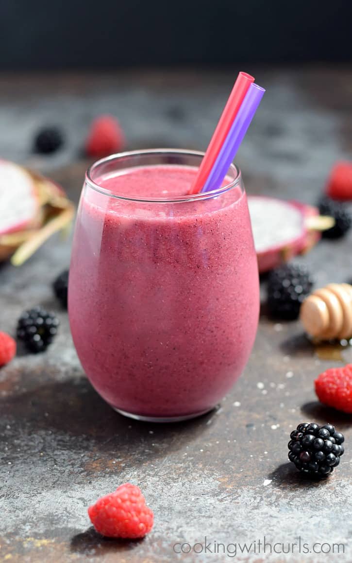 Dragon Fruit Smoothie in a glass surrounded by fresh berries.