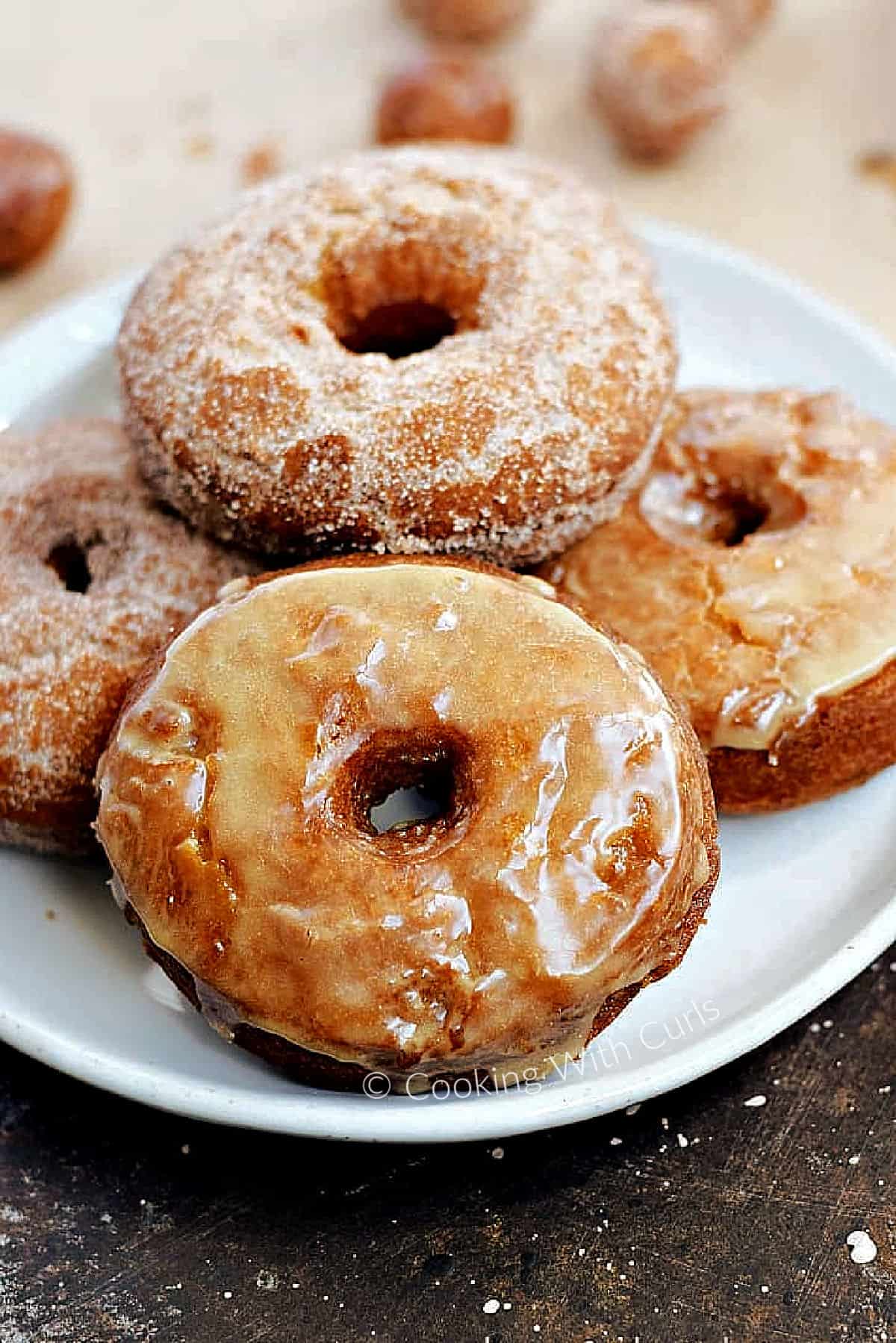 Glazed and sugar coated apple cider doughnuts on a plate. 