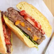 A cheese stuffed burger sliced in half on parchment paper.