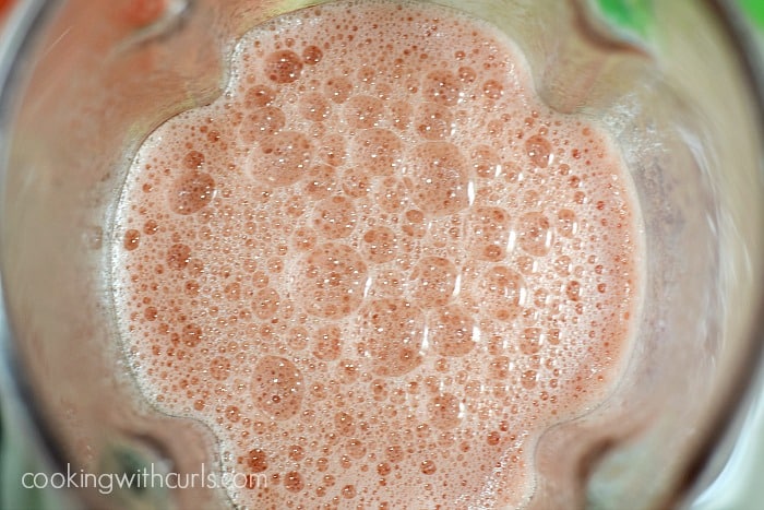 Looking down into a frothy pink drink in a blender.