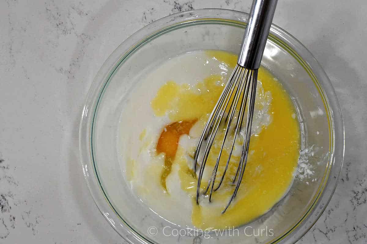 Eggs, buttermilk, and melted butter in a mixing bowl with a wire whisk.