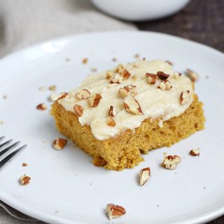! Pumpkin Spice Bar on a white plate with pecans and additional frosting in the background in small white bowls