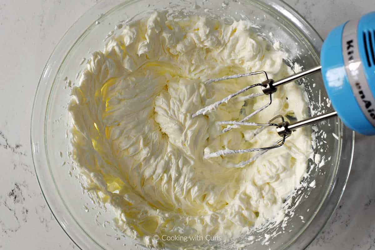 Whipped cream and cream cheese in a mixing bowl.