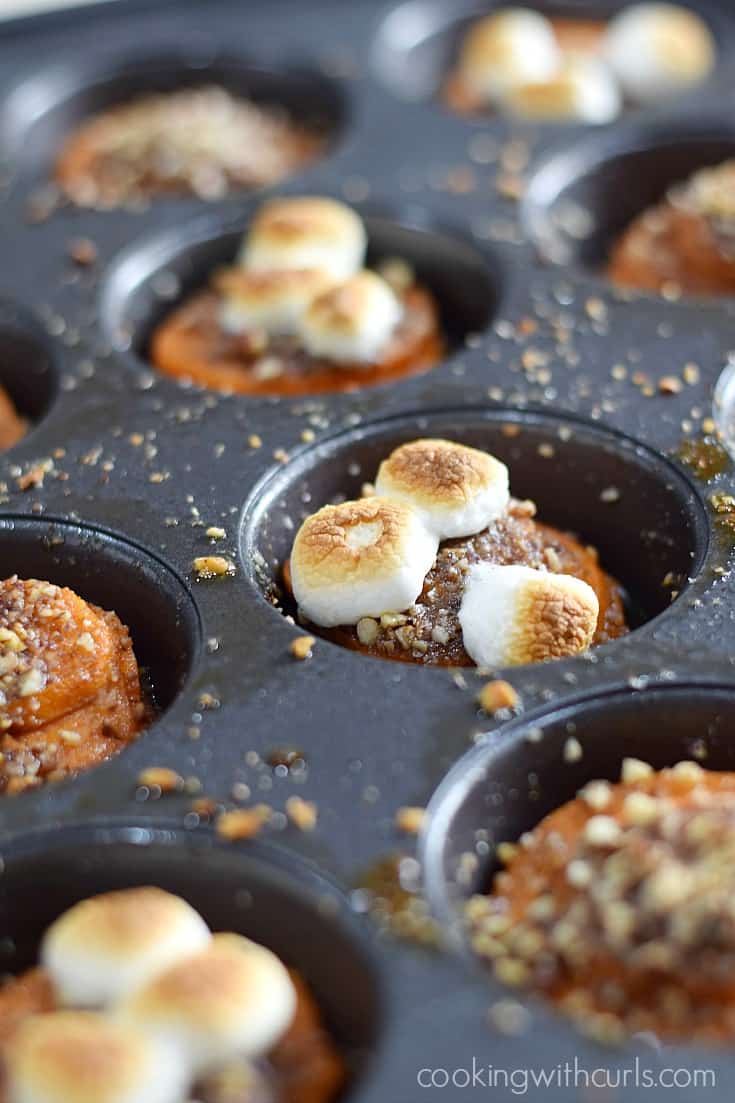 Candied sweet potato stacks topped with toasted mini marshmallows in a muffin tin.