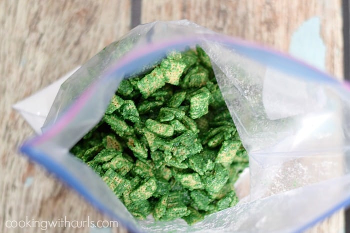 Looking down at green coated cereal in a zipper top bag on top of powder sugar.