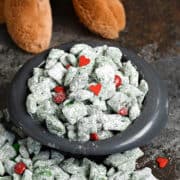 Grinch Puppy Chow overflowing out of a small dog bowl with a stuffed max doll in the background.