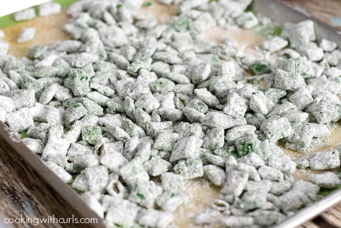 Grinch Puppy Chow spread out over a silicone lined baking sheet.