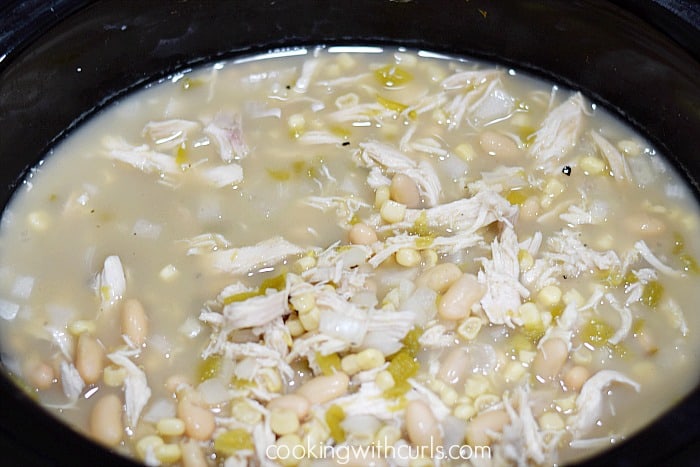 Shredded chicken, white beans, and corn chili in a slow cooker.