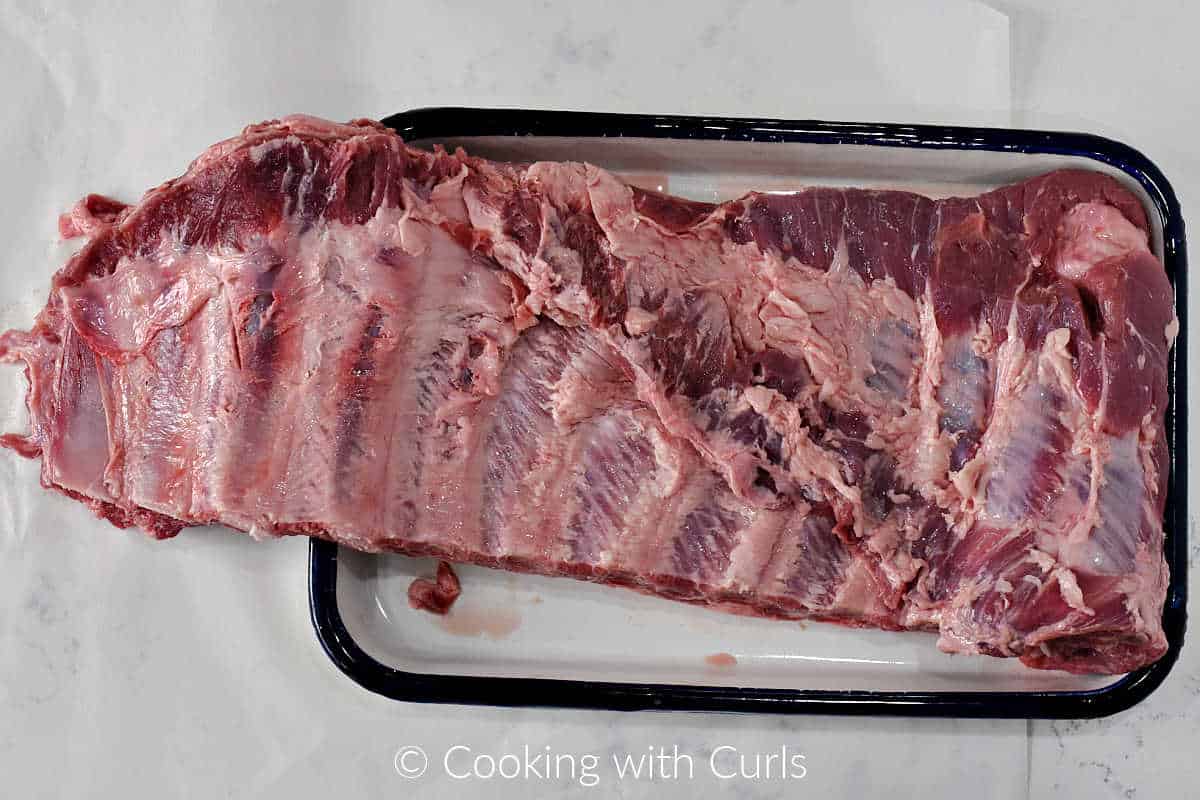 A rack of ribs with the membrane removed laying on a tray.