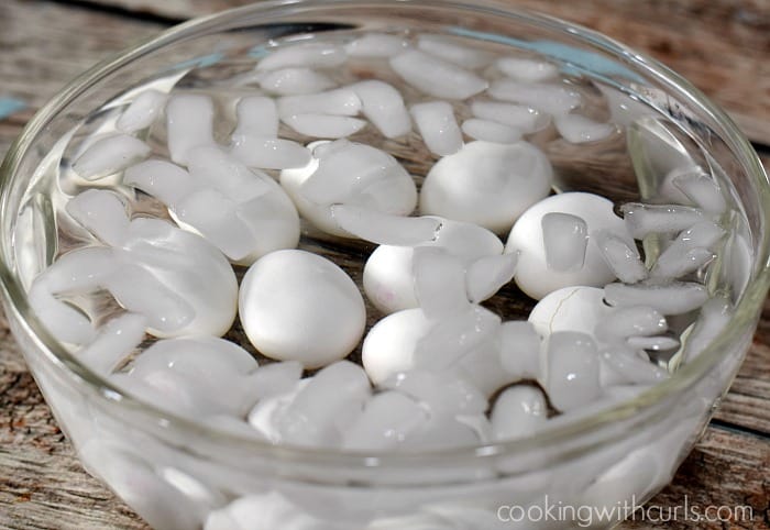A large bowl with ice cubes, water, and hard boiled eggs.