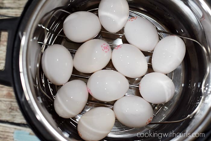One dozen eggs on a trivet over water in an Instant Pot.