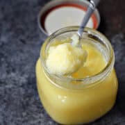 Clarified butter on a spoon resting on the edge of a jar.