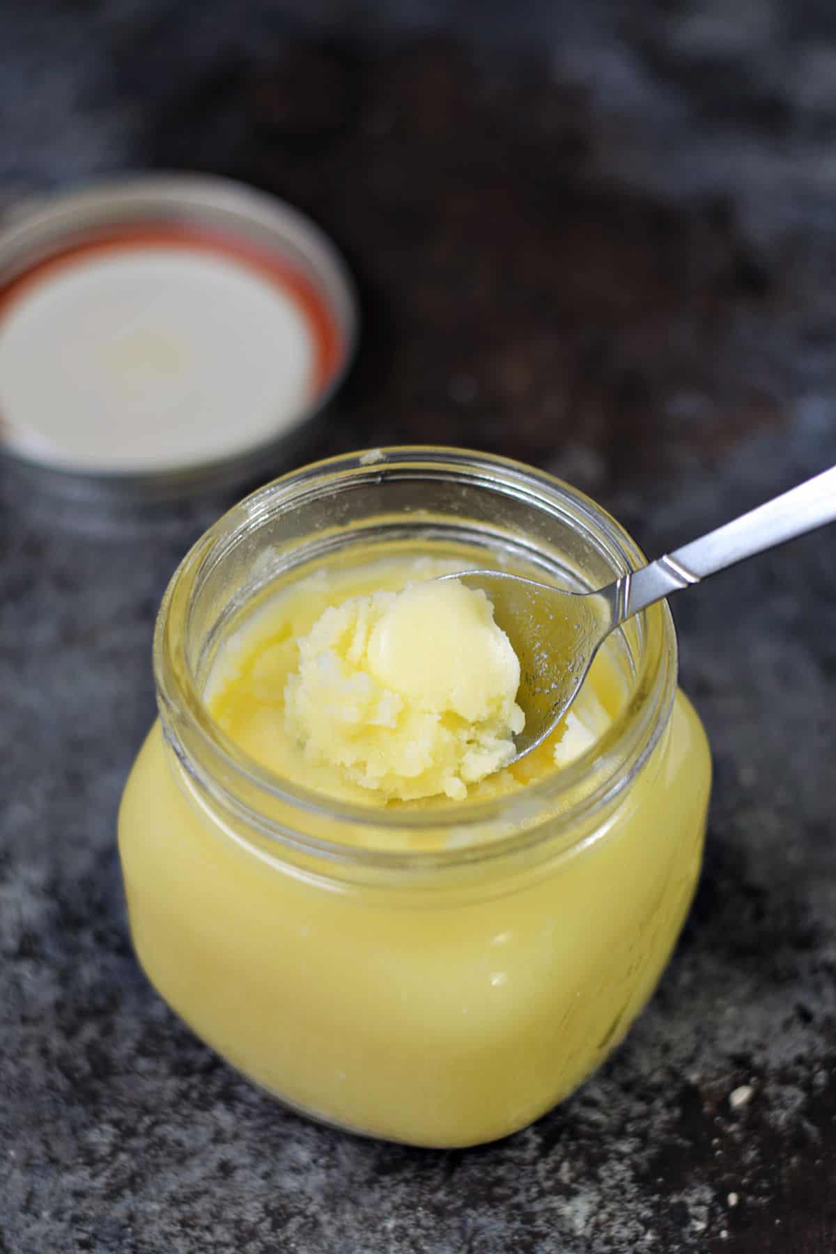 Clarified butter scooped with a spoon in a small jar.