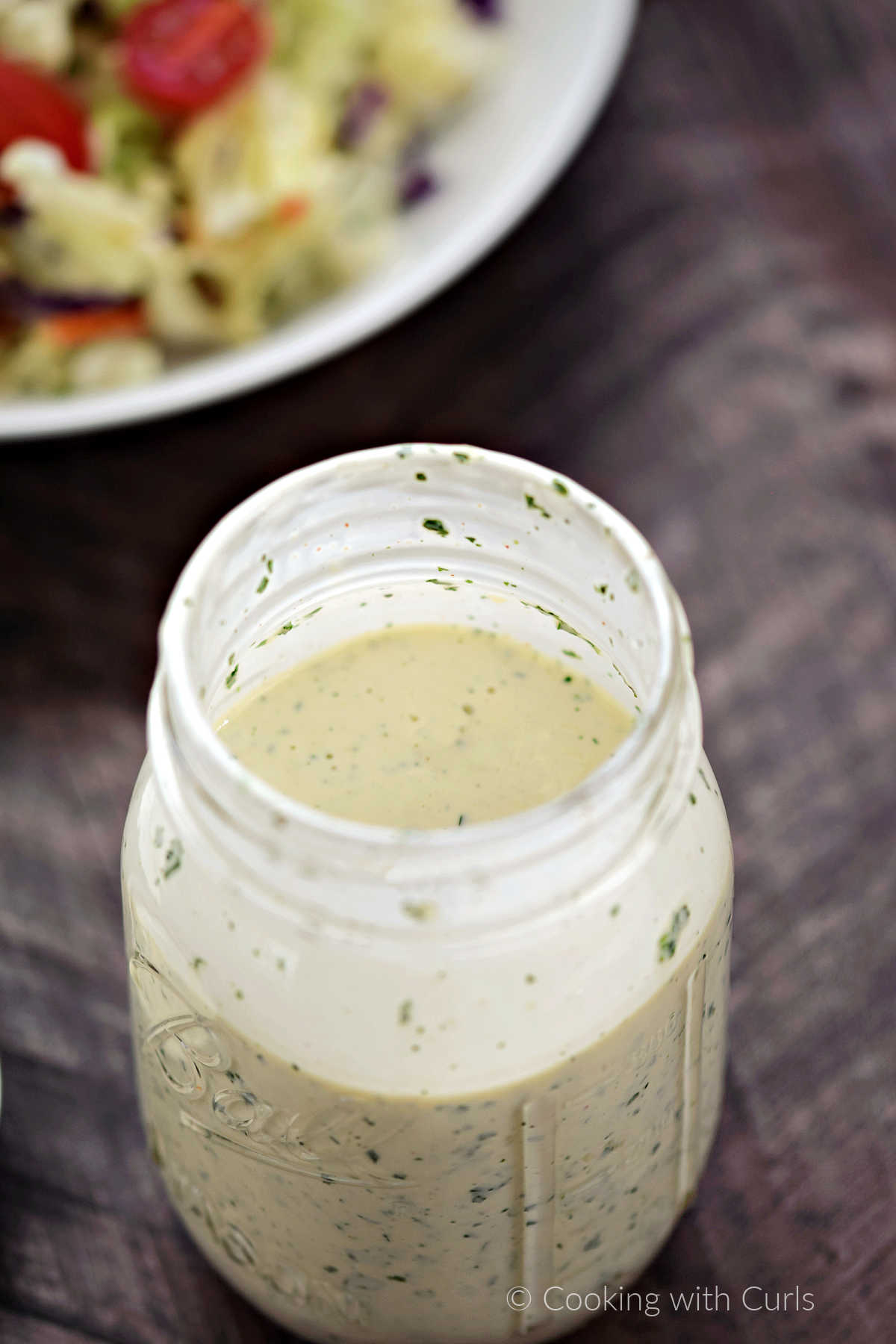 Looking down into a glass jar filled with ranch dressing.