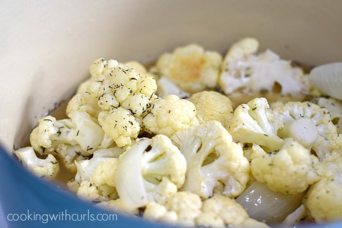 Roasted cauliflower, herbs and stock in a large Dutch oven.