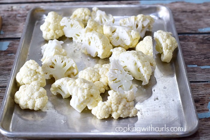 Raw chunks of cauliflower on a baking sheet.