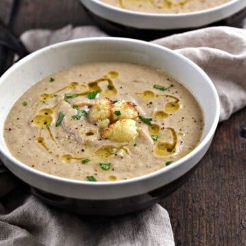 A bowl of roasted cauliflower and garlic soup topped with roasted cauliflower croutons.