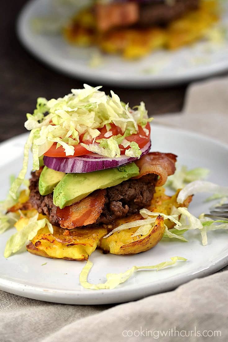 Smashed Potato topped with a  burger, bacon, avocado slices, red onion, tomato, and shredded lettuce.