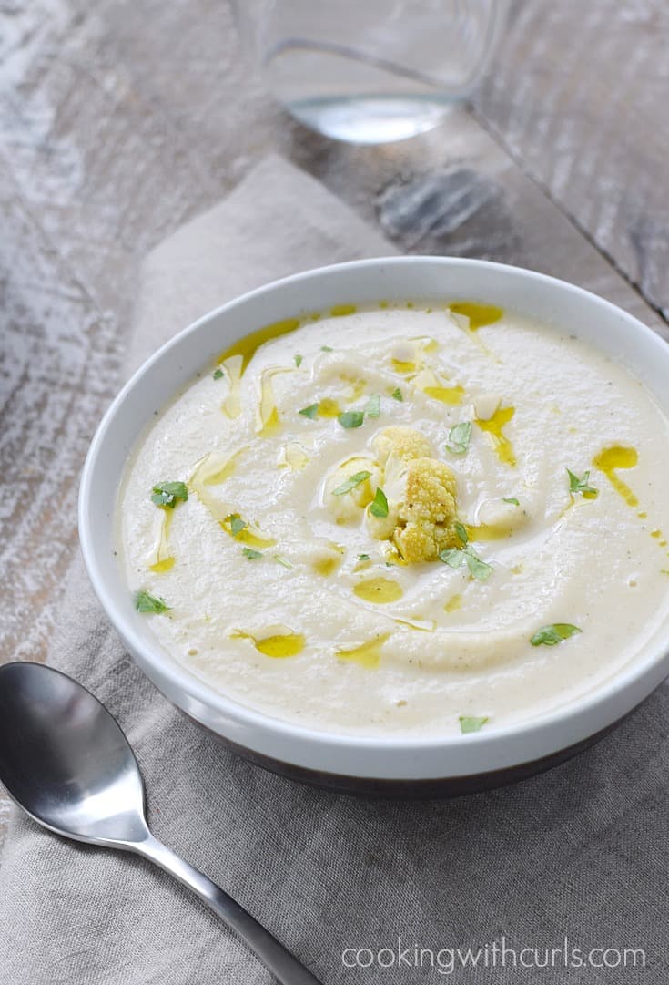 A bowl of creamy cauliflower soup drizzled with olive oil and topped with roasted cauliflower.