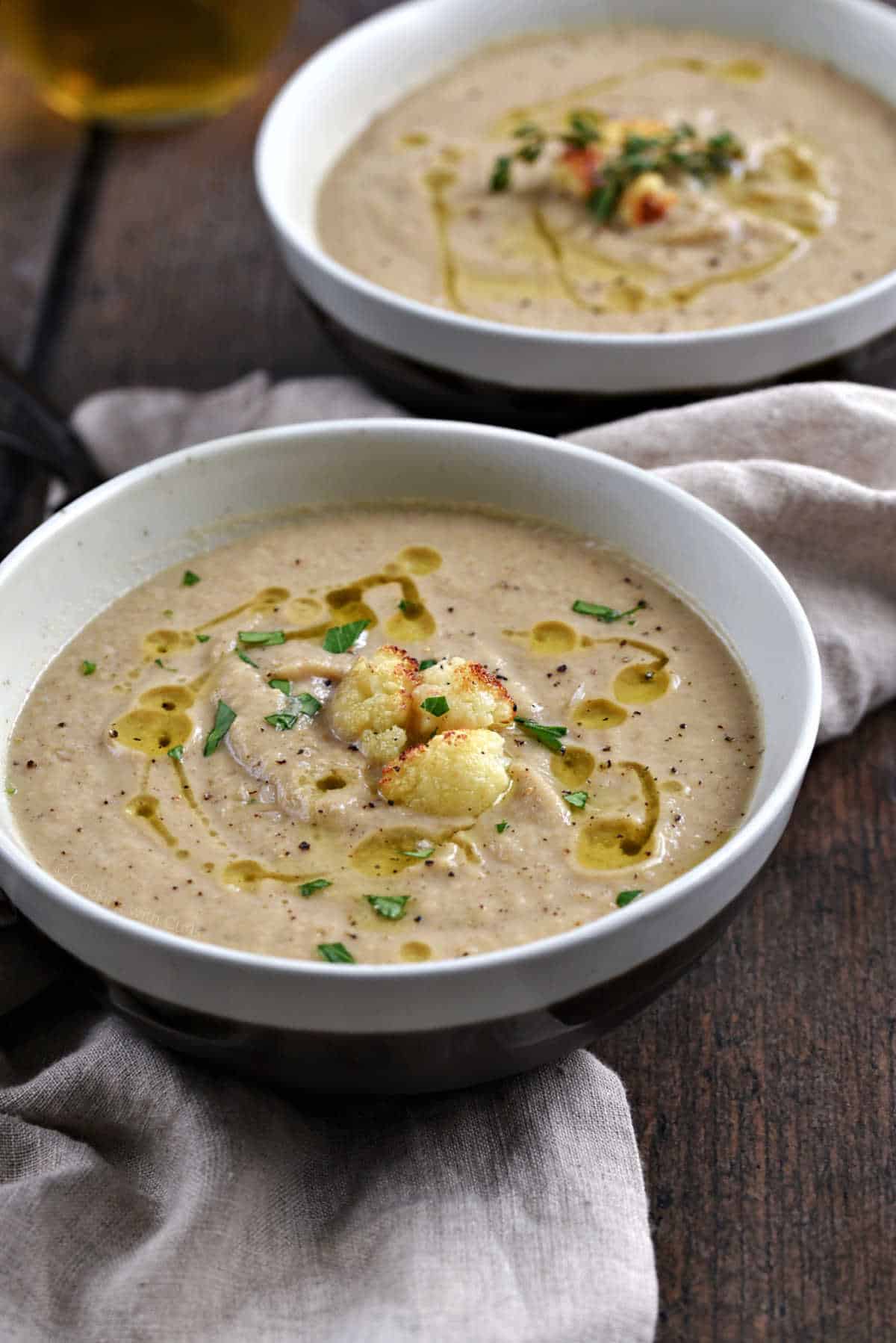 Two bowls of roasted cauliflower and garlic soup topped with roasted cauliflower croutons.