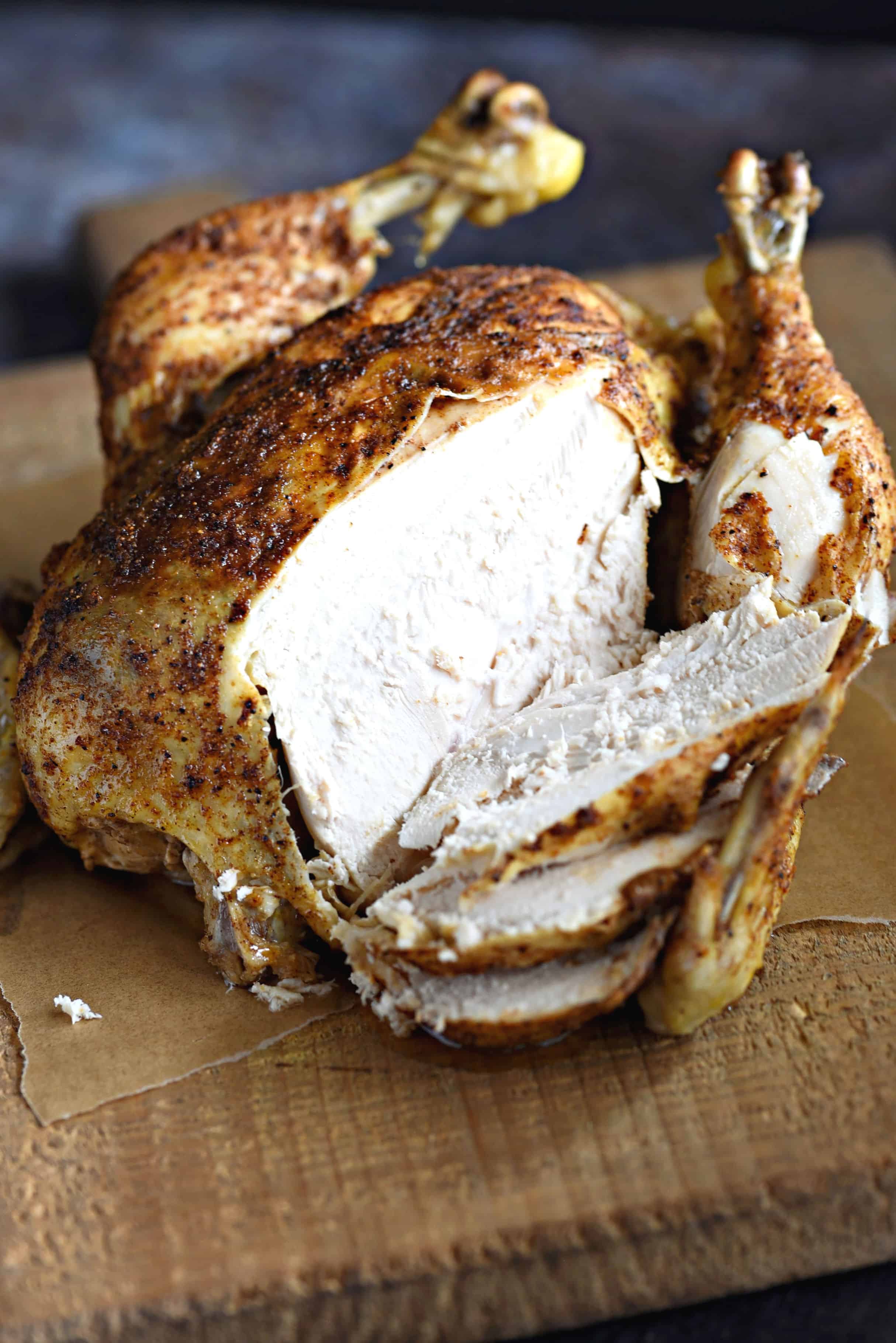 moist and delicious Faux-tisserie Chicken sliced on a wooden cutting board.