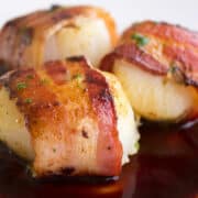 Three bacon wrapped scallops in pomegranate sauce.