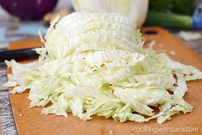 Napa Cabbage sliced into strips on a cutting board.