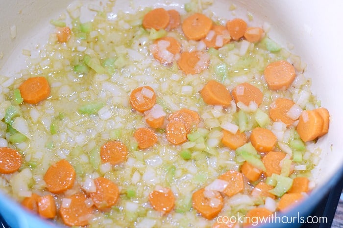 Chopped onion, celery, and carrots cooking in oil in a large Dutch oven.