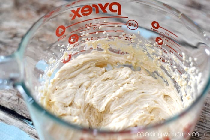 Maple frosting beaten together in a large glass measuring cup.