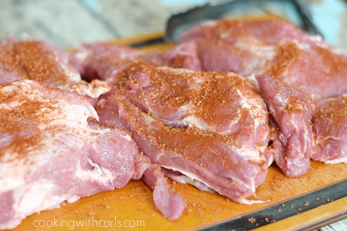 Pork pieces seasoned with smoked sea salt mixture on a cutting board. 