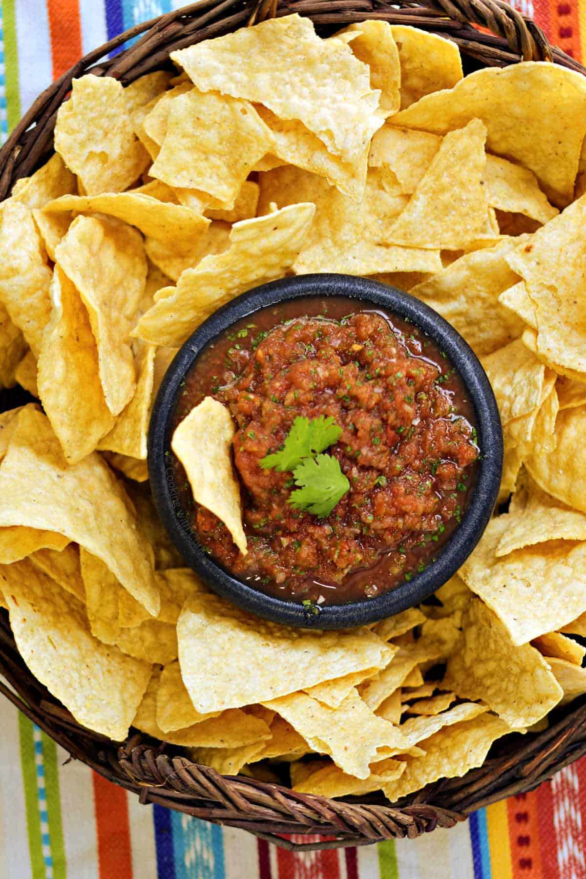 A small bowl of restaurant style salsa roja surrounded by tortilla chips.