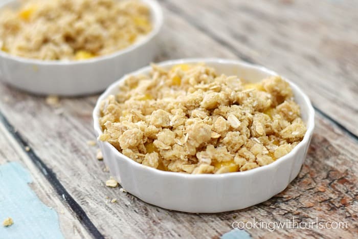 Crumble topping over the fresh peaches in two small baking dishes.