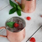 Two raspberry moscow mules in copper mugs.